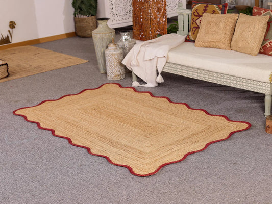 Beige area rug with red border on a gray carpeted floor