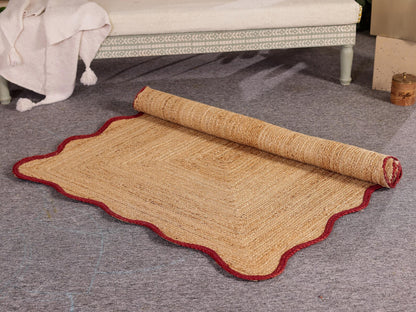 Rolled-up natural fiber rug with red border on a gray floor.