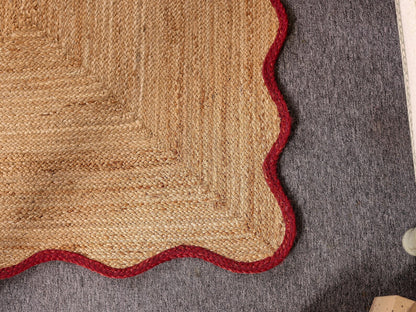 Close-up of a textured rug with a red border on a gray surface