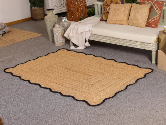 Beige area rug on a gray carpet with a sofa and decorative items in the background