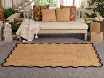 Beige woven rug on a gray floor with a couch and decorative pillows in the background.