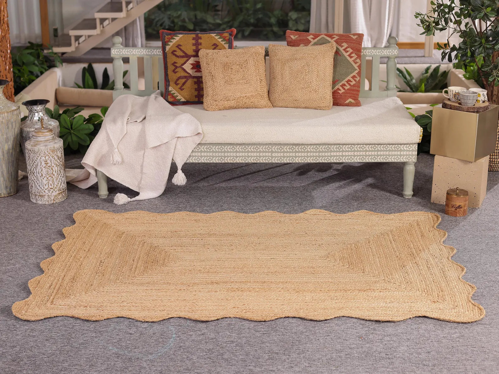 Beige jute rug on a gray floor with a wicker bench and decorative pillows in the background.