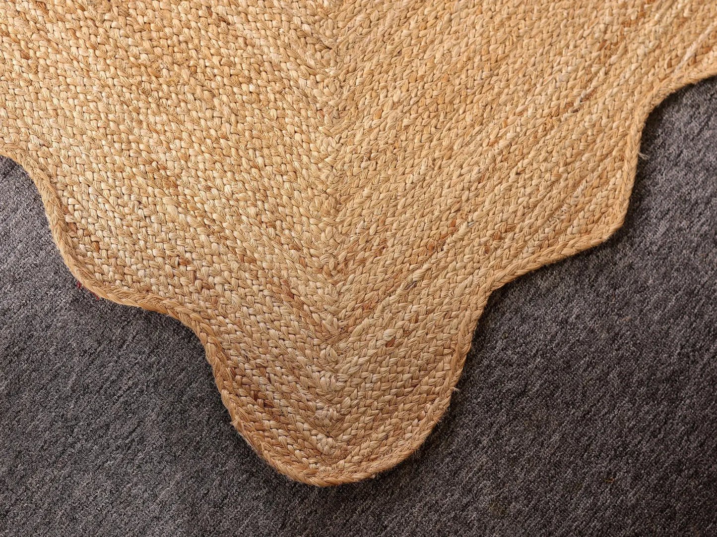 Close-up of a textured beige rug corner on a dark surface