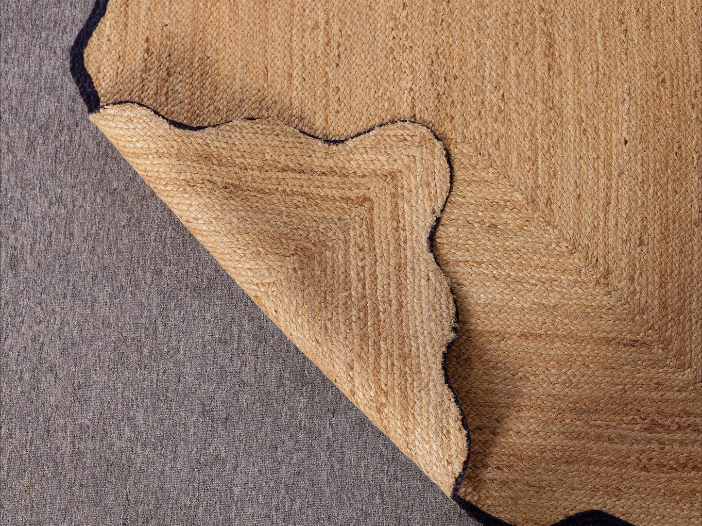 Close-up of a brown textured rug corner on a gray surface