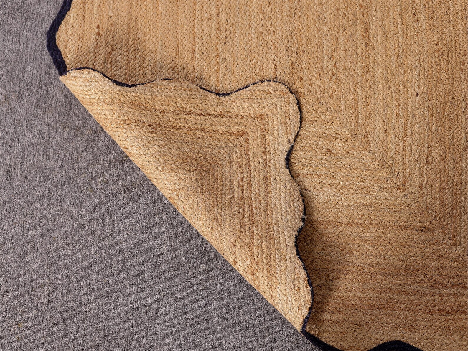 Close-up of a brown textured rug corner on a gray surface