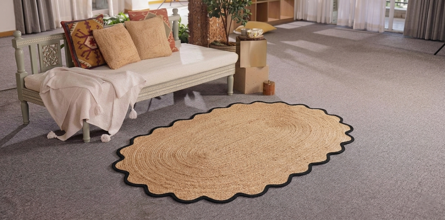Beige woven rug on a gray carpeted floor with a couch and pillows in the background.