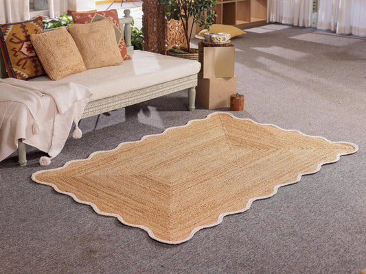 Beige woven rug on a gray carpeted floor with a couch and decorative items in the background.