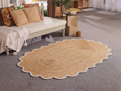 Round beige rug on a gray carpeted floor with a couch and decorative items in the background.
